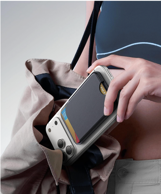 Person holding a phone with a protective case, leaning against a beige bag.