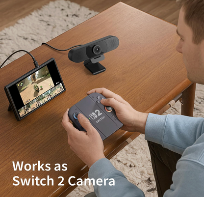 Person using a gaming controller with a screen displaying a game, placed on a wooden table.