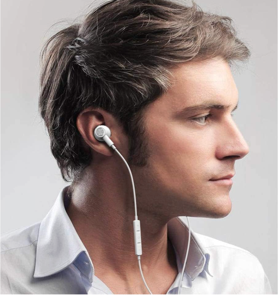 A man in profile wearing white wired in-ear earphones with a white inline remote, against a light gray background.